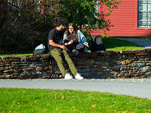 two students sitting on a wall