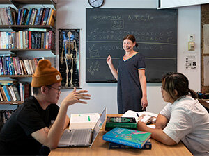 students and faculty in a classroom learning in front of a blackboard