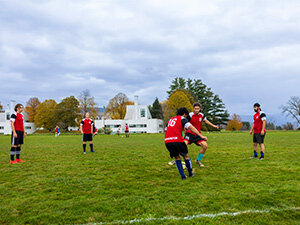 students in red jerseys playing soccer on a green field