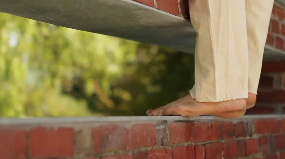 Close-up of dancer's bare feet on brick wall