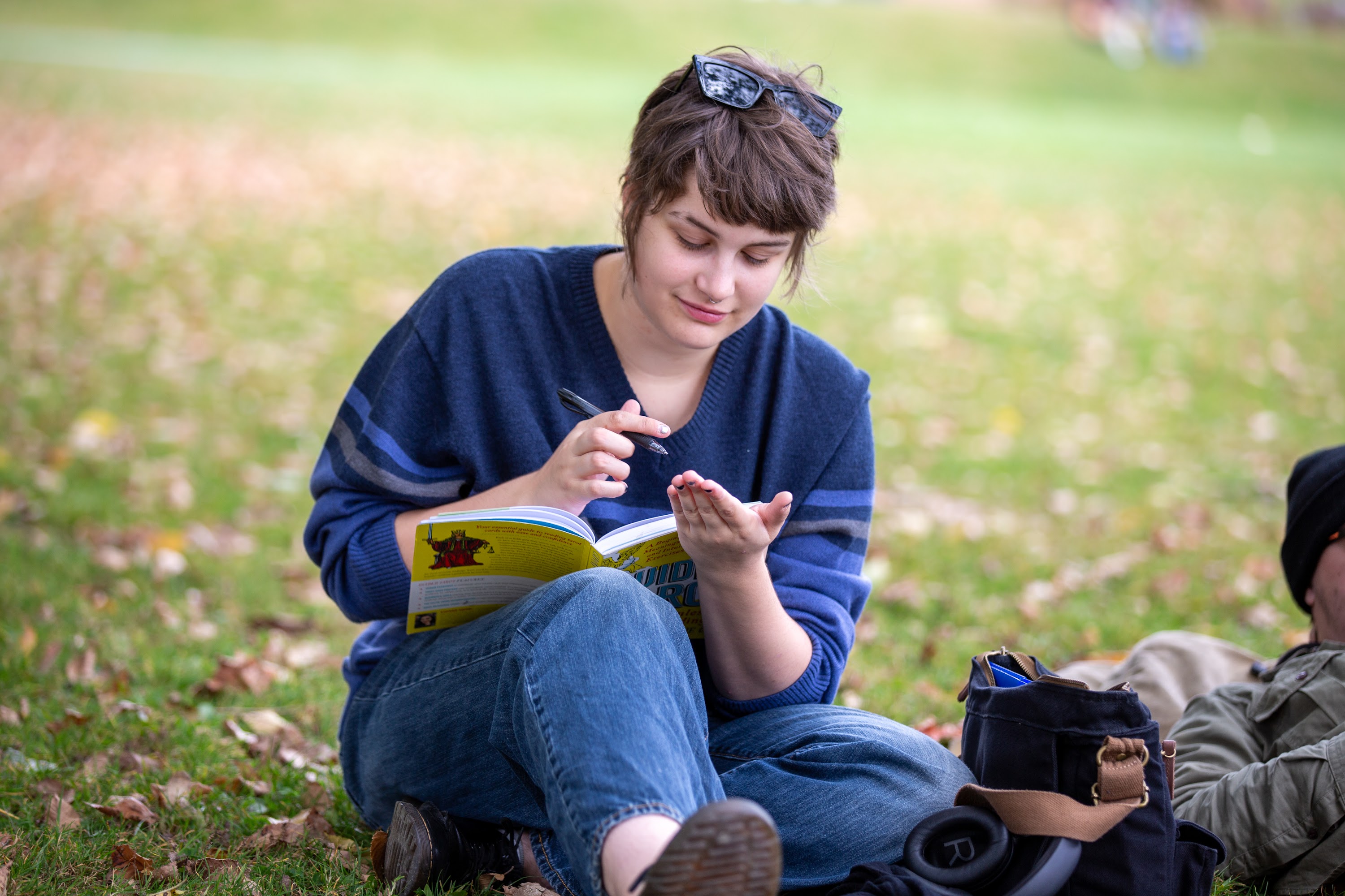 Student sitting on grass with pen and book