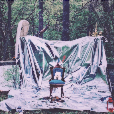 a forest scene draped in a white sheet with a chair in the middle