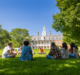 Students gather in a small group and sit in a circle on the lawn