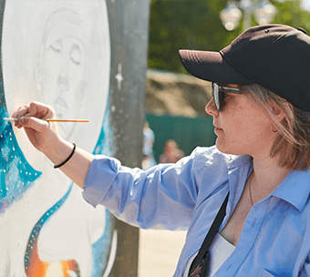 a student volunteers and paints a mural