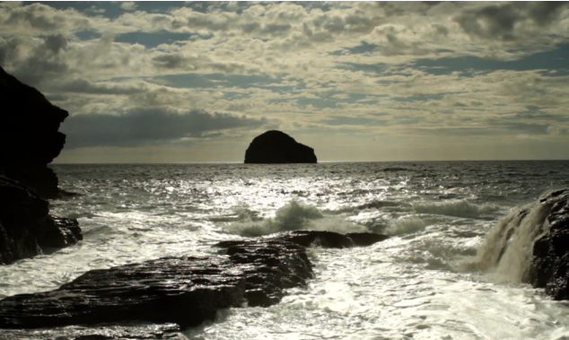 ocean with waves and big boulder in distance