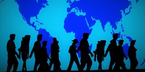 Black figures walking in front of a blue wall featuring the map of the world