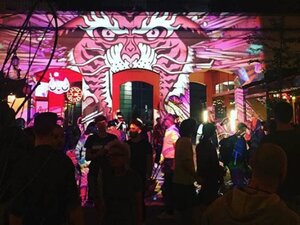 a crowd of people standing in front of a projection of a pink tiger on a wall