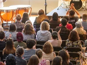 students sitting in an audience clap