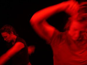 two women mid-movement dancing with red light and coloring