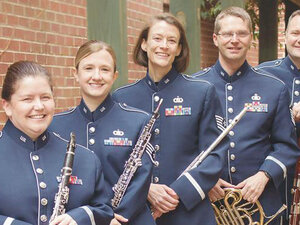 the heritage winds group in blue uniforms with their instruments 
