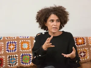 Woman in black sweater sitting on a sofa with a quilt