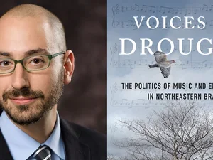 bald man with glasses in a suit with a book cover featuring a tree and a bird