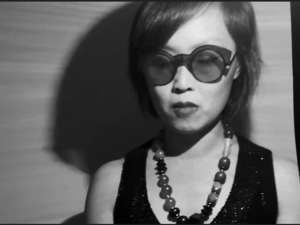 black and white photo of woman with sunglasses and a bead necklace