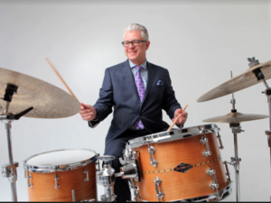 man in a suit playing a drum kit