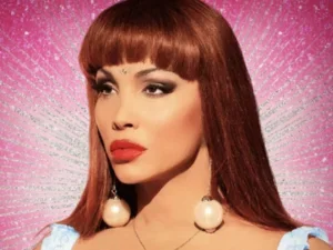 headshot of woman with red hair and bold makeup on a pink background