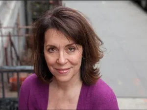 smiling woman in fuchsia cardigan seen from above on what appears to be a city sidewalk
