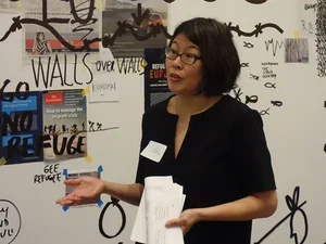 woman with short dark hair and glasses presenting