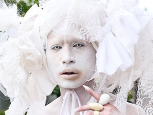 person wearing white face paint and elaborate white headdress 