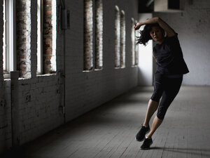dancer, body twisted mid-move in an empty industrial space 