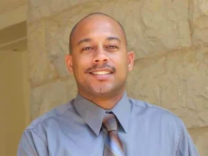 man wearing blue shirt smiles at camera