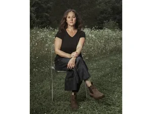 Lisa Olstein sitting in a folding chair on the grass