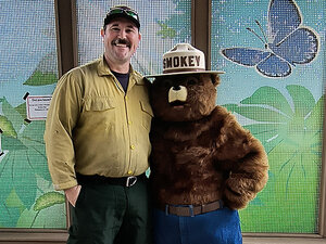 Tyler Briggs and Smokey the Bear against a flowery background 