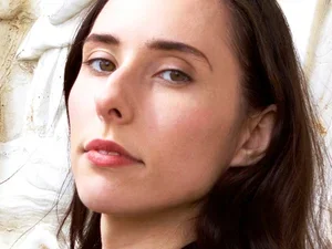 Nicolette Polek '15 woman with slim oval face and straight brown hair stares into camera