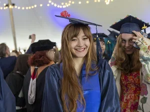 A Bennington graduate smiles wide with a clownfish perched on her cap