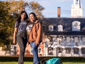 Two students smile at the camera in front of Commons