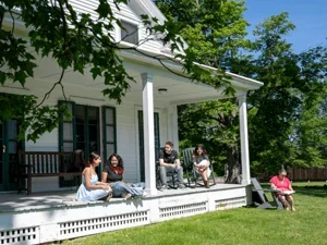 Students sit together on the porch of Crockett on a sunny summer day