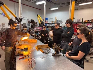 Image of River Valadez ’20 (MFT ’19) leads Fellows in a flameworking class at Urban Glass.