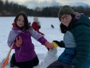Image of Sofia Mirenda building snowman with student
