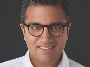 Asad Ayaz white shirt and glasses with a dark background 