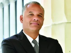 Man wearing suit crosses arms and looks at camera