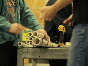 Students building an instrument out of PVC tubing