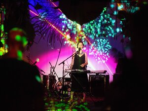 Singer Mari Cook performing in front of a colorful projection at Rubulad