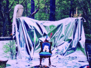 a forest draped in a white sheet with a chair at the center