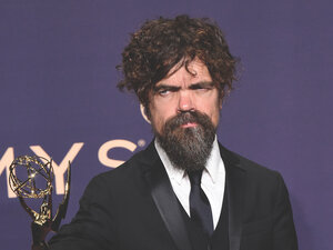 man with brown hair and beard holds emmy on the red carpet, purple background