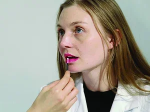 Close up of a woman's face while someone else applies lip gloss to her lips