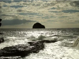 ocean with waves and big boulder in distance