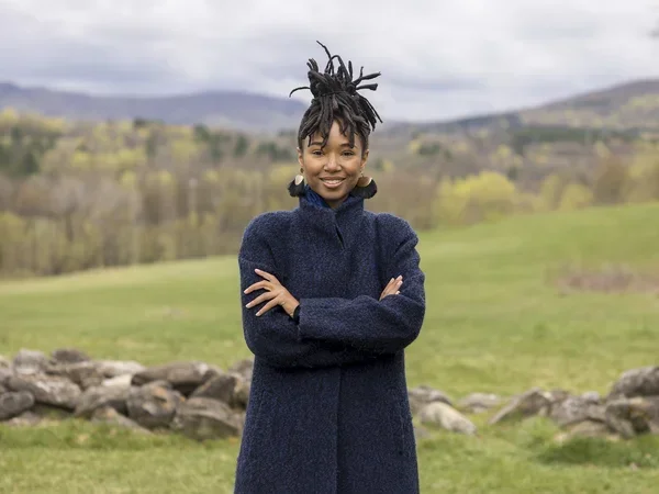 Outdoor portrait, with mountains and clouds in the background, of being, the artist formerly known as Kriss Mincey