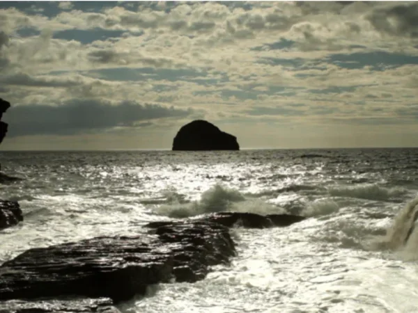 ocean with waves and big boulder in distance