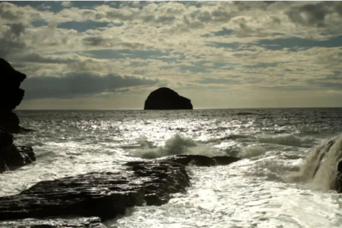 ocean with waves and big boulder in distance
