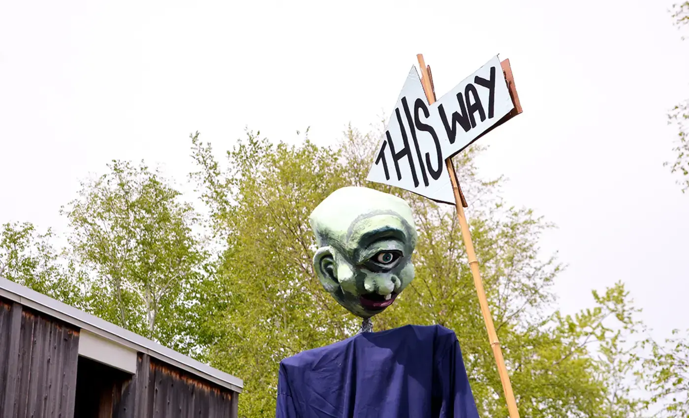 Puppet with sign that says "This Way"