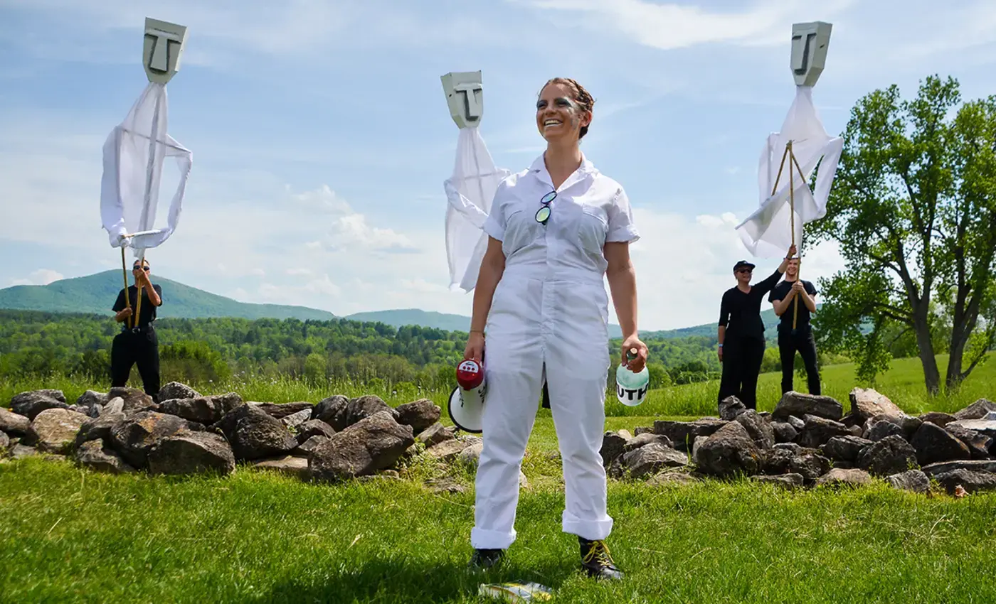 Drama student standing in front of her life-sized puppets on Commons Lawn