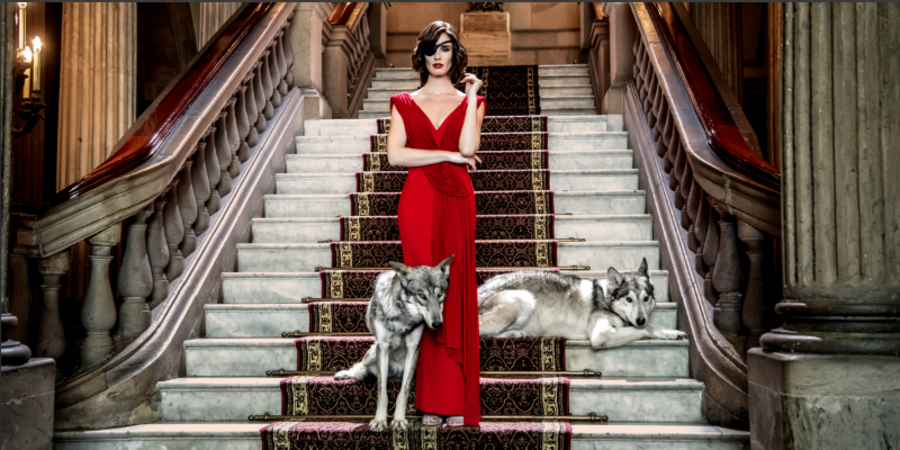 woman in fancy red dress on fancy grand staircase with wolves