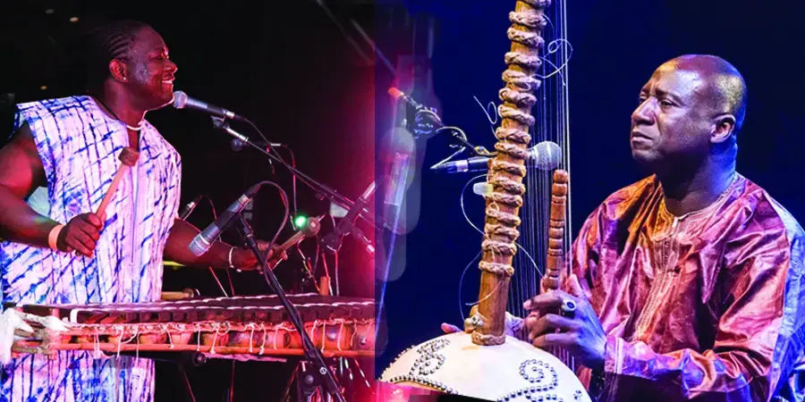 Two men wearing traditional African dress play the balafon and the kora