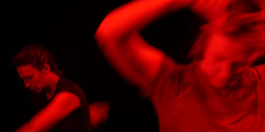two women mid-movement dancing with red light and coloring