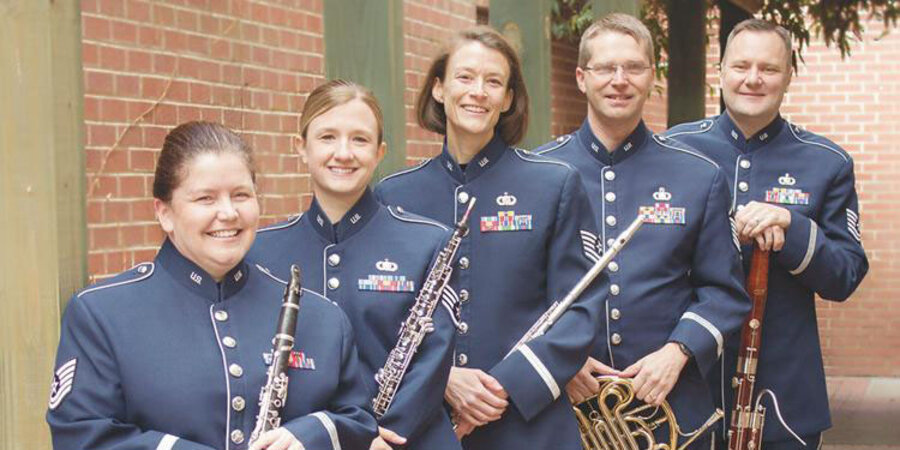 the heritage winds group in blue uniforms with their instruments 