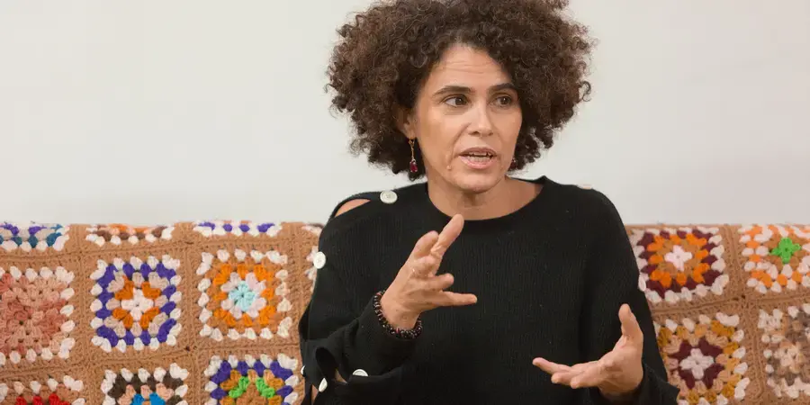 Woman in black sweater sitting on a sofa with a quilt